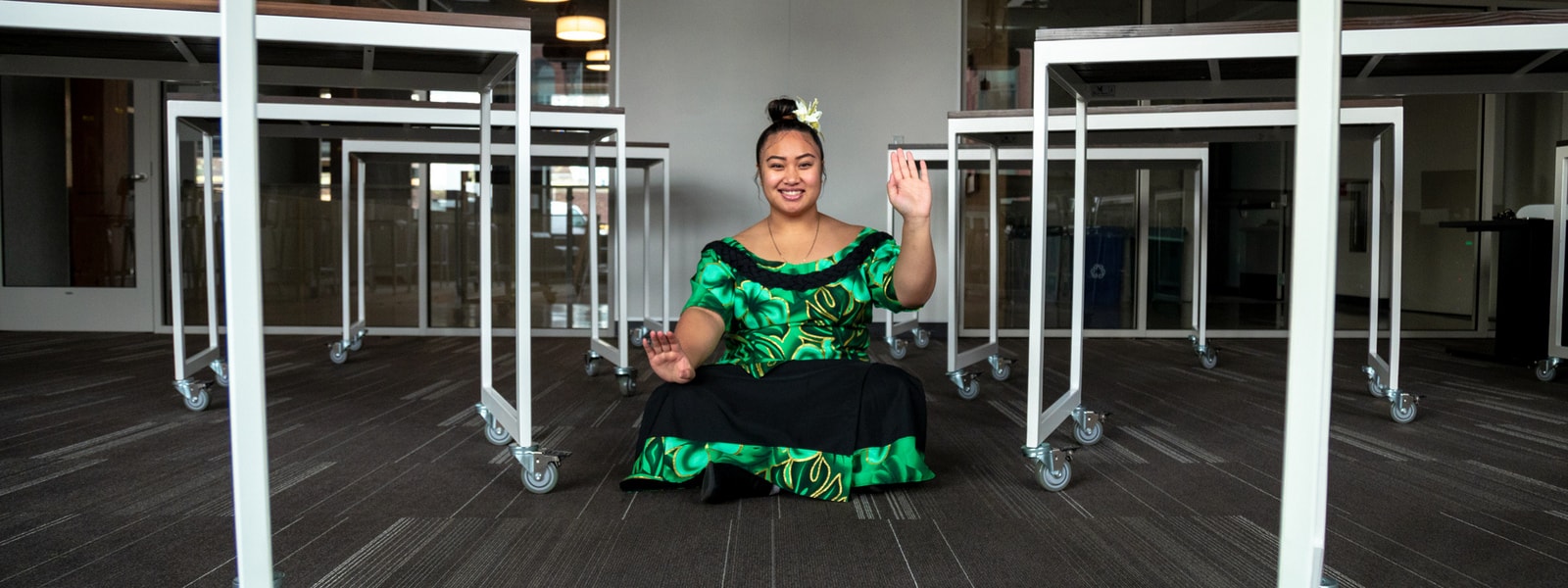 Nedralani Mailo wearing a traditional Samoan puletasi with a sei in her hair, performing a common hand movement found in traditional Samoan dances.