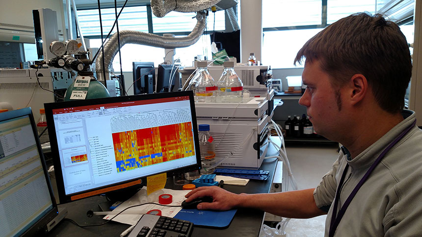 Dr. Ed Kolodziej, UW Tacoma Science & Mathematics and Center for Urban Waters, in a lab with computer monitors and analytical equipment.