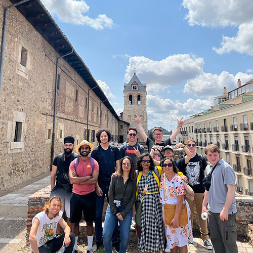 A group of UW Tacoma students, faculty and staff stand outside the UW's León Center in Spain. The group is in front of a large gothic type stone building. 