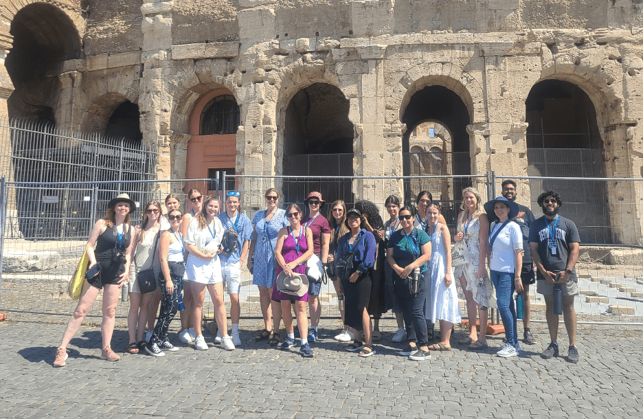 A group of people posing for a photo outside of the Colosseum in Rome