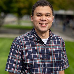 Headshot of UW Tacoma faculty member Lorne Arnold. Arnold has short black hair and is wearing a plaid button up. He is smiling.