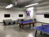 Photo of UWY space, showing pool table, ping pong table, air hockey table, couches, tables, chairs, and TVs.