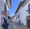 Image of cobblestone street in Peru with white buildings and signs along the walls