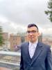 Image of student in suit smiling with UW Tacoma in the background