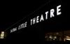 The exterior sign for the Tacoma Little Theatre. It is dark outside. The letters are white and big.