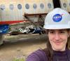 UW Tacoma mechanical engineering student Amy Keller at NASA Langley Research Center standing in front of drop-tested aircraft remains.