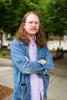 Will Taylor stands outside with his arms crossed, wearing a jean jacket and purple shirt.