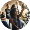 people in a workshop with a natural-haired black woman raising her hand