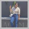 a photo of Nupur Singh. They are wearing a white button down and blue jeans and showing a peace sign in front of the W statue on the UW Tacoma campus.