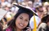 Smiling UW Tacoma student in cap and gown, holding smartphone to ear.